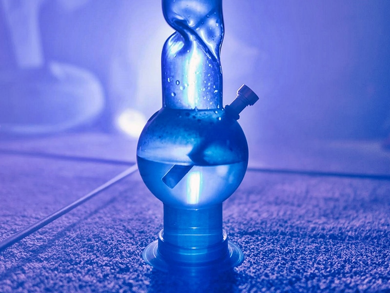 Blue glass bong with removable downstem on carpeted floor