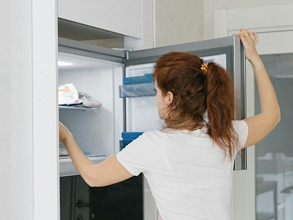 Red-haired woman opening kitchen freezer door