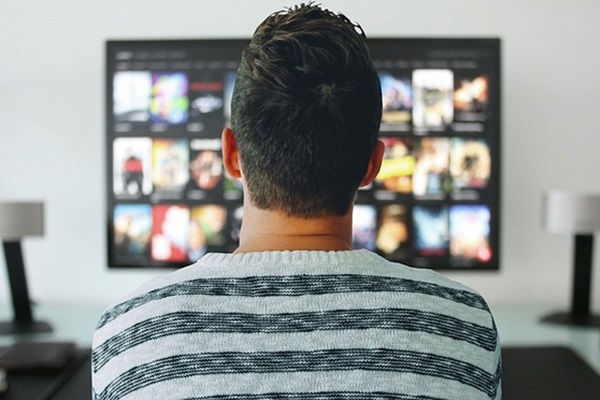 Short-haired man in striped sweater watching television